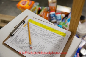 A clip board showing the food item and quantities for the Koyuk checkpoint sits on a box  at the Airland Transport's sort facility where volunteers sort and package people food & accompanying supplies for the trail volunteers to eat during the race at the 20+ checkpoints on Friday February 14, 2014.  Iditarod Sled Dog Race 2014PHOTO BY JEFF SCHULTZ/IDITARODPHOTOS.COM  USE ONLY WITH PERMISSION