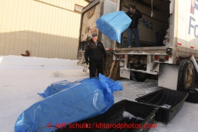 February 16, 2013  Race Manager and Marshal Mark Nordman unloads bales of straw from a van at the Willow airport to be flown flown to the 4 checkpoints on the east side the Alaska Range as chief pilot Bert Hanson looks on. Photo Copyright Jeff Schultz  -- Do not reproduce without written permission