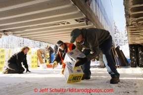 February 16, 2013 Volunteer Al Ostrowski unloads HEET from a van and slides it under another van to more volunteers  at the Willow airport as musher food, straw, HEET and people food is flown to the 4 checkpoints on the east side the Alaska Range. Iditarod 2013   Photo Copyright Jeff Schultz  -- Do not reproduce without written permission