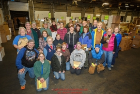 Iditarod volunteers pose for a group photo as they sort and repackage human food and supplies for the trail volunteers to eat at each of the checkpoints on the 2017 Iditarod. The sorting is going on at the Airland Transport warehouse facilities in Anchorage Alaska on Friday  February 17, 2017.Photo by Jeff Schultz/SchultzPhoto.com  (C) 2017  ALL RIGHTS RESVERVED
