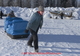 Saturday February 18, 2012   Volunteers Kim Menster (R) and Andi Malard push a sled of straw to a waiting plane at the Willow airport as the straw, musher food bags, lathe, people food and supplies begin to be flown out by the Iditarod volunteer Air Force  to checkpoints along the trail.