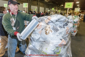 Vounteer Daniel Page shrink-wraps a pallet of musher food bags at Airland Transport warehouse in Anchorage on Wednesday February 18th prior to Iditarod 2015.(C) Jeff Schultz/SchultzPhoto.com - ALL RIGHTS RESERVEDDUPLICATION PROHIBITED WITHOUT PERMISSION