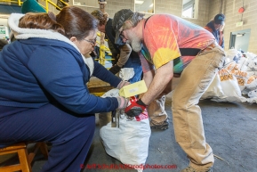 Volunteers Bryan Nelson (r) and Mo Pedigo (l) add postage tags to bags as part of a  team of volunteers unload, sort, weigh, tag and palletize thousands of musher food drop bags at Airland Transport warehouse in Anchorage on Wednesday February 18th prior to Iditarod 2015.(C) Jeff Schultz/SchultzPhoto.com - ALL RIGHTS RESERVEDDUPLICATION PROHIBITED WITHOUT PERMISSION