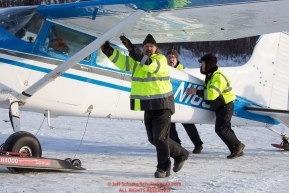 Volunteer Iditarod Air Force Director of Maintenance, Loren Gerrety, and pilots Greg Fishcer and Daniel Hayden push Fischer's plane to a holding area at the Willow, Alaska airport during the Food Flyout on Saturday, February 20, 2016.  Iditarod 2016