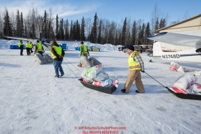 Volunteers move and hay, musher drop bags, people food and HEET to waitng Iditarod Air Force planes at the Willow, Alaska airport during the Food Flyout on Saturday, February 20, 2016.  Iditarod 2016