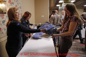 Musher Angie Taggart recieves a gift of a duffle bag given to all mushers from sponsor ExxonMobil during the mandatory musher meeting at the Millenium hotel two days prior to the start of Iditarod 2013.  Thursday February 28, 2013Photo (C) Jeff Schultz/IditarodPhotos.com  Do not reproduce without permission