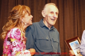 Thursday February 28, 2013  Longtime Skwentna checker Joe Delia is all smiles as he stands with DeeDee Jonrowe and is presented, along with his wife Norma, with the Iditarod Trail Founders Award at the musher drawing banquet held at the Dena'ina Convention Center in Anchorage two days prior to the start of Iditarod 2013.Photo (C) Jeff Schultz/IditarodPhotos.com  Do not reproduce without permission