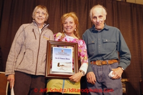 Thursday February 28, 2013  DeeDee Jonrowe (center) presents the Iditarod Trail Founders Award to Joe and Norma Delia, longtime checkers at Skwentna at the musher drawing banquet held at the Dena'ina Convention Center in Anchorage two days prior to the start of Iditarod 2013.Photo (C) Jeff Schultz/IditarodPhotos.com  Do not reproduce without permission