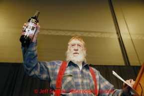 Thursday February 28, 2013  Dick Newton, widower of the late Jan Newton, holds a bottle of wine with his wife's photo on it as the honorary musher of the 2013 race at the musher drawing banquet held at the Dena'ina Convention Center in Anchorage two days prior to the start of Iditarod 2013.Photo (C) Jeff Schultz/IditarodPhotos.com  Do not reproduce without permission