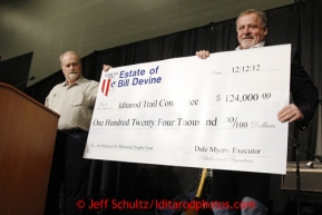 Thursday February 28, 2013  Dale Myers, (L) executor of the estate of the late Bill Devine, original artist of the Iditarod,  presents a $124,000 check to Iditarod Executive Director Stan Hooley to be used to perpetuate the Joe Redington Sr. trophy at the musher drawing banquet held at the Dena'ina Convention Center in Anchorage two days prior to the start of Iditarod 2013.Photo (C) Jeff Schultz/IditarodPhotos.com  Do not reproduce without permission