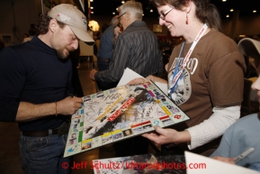 Thursday February 28, 2013  Veteran musher Jason Mackey signs an Iditarod Monopoly game for a fan at the musher drawing banquet held at the Dena'ina Convention Center in Anchorage two days prior to the start of Iditarod 2013.Photo (C) Jeff Schultz/IditarodPhotos.com  Do not reproduce without permission