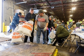 Iditarod volunteers unload, weigh, organize and stack the mushers food bags destined for the checkpoints on the 2017 Iditarod at the Airland Transport warehouse facilities in Anchorage Alaska.Wednesday February 15, 2017.Photo by Jeff Schultz/SchultzPhoto.com  (C) 2017  ALL RIGHTS RESVERVED