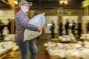 An Iditarod volunteer moves a food drop bag to its proper location as others unload, weigh, organize and stack the mushers food bags destined for the checkpoints on the 2017 Iditarod at the Airland Transport warehouse facilities in Anchorage Alaska.Wednesday February 15, 2017.Photo by Jeff Schultz/SchultzPhoto.com  (C) 2017  ALL RIGHTS RESVERVED