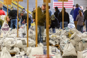 An Iditarod volunteer moves a food drop bag to its proper location as others unload, weigh, organize and stack the mushers food bags destined for the checkpoints on the 2017 Iditarod at the Airland Transport warehouse facilities in Anchorage Alaska.Wednesday February 15, 2017.Photo by Jeff Schultz/SchultzPhoto.com  (C) 2017  ALL RIGHTS RESVERVED