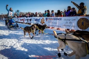 Larry Daugherty waves to the crowd as he runs down the start chute during the Re- Start of the 2016 Iditarod in Willow, Alaska.  March 06, 2016