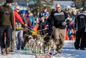 Volunteer dog handler Travis Taylor helps walk Dag Torulf Olsen's team into the start line during the Re- Start of the 2016 Iditarod in Willow, Alaska.  March 06, 2016