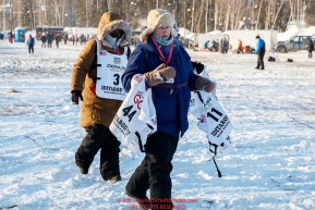 Volunteers carry bibs in the staging area prior to the re-start of the 2017 Iditarod in Fairbanks, Alaska at PikeÂs Landing on Monday March 6, 2017.Photo by Jeff Schultz/SchultzPhoto.com  (C) 2017  ALL RIGHTS RESVERVED