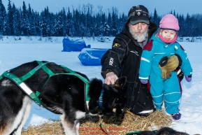Long-time lead Nikolai checker John Runkle shows his 2-year old grandaughter Anavay Runkle a pair of Ryan Redington dogs at the Nikolai checkpoint during the 2018 Iditarod race on Tuesday March 06, 2018. Photo by Jeff Schultz/SchultzPhoto.com  (C) 2018  ALL RIGHTS RESERVED