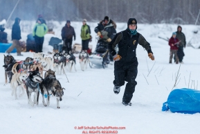 Trail volunteer Erica Goad runs in front of Ray Redington Jrs. team to a parking spot at the Nikolai checkpoint during the 2018 Iditarod race on Tuesday March 06, 2018. Photo by Jeff Schultz/SchultzPhoto.com  (C) 2018  ALL RIGHTS RESERVED