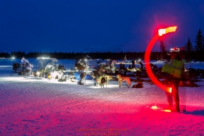 Volunteer Mark Greene waves a red light stick to show the way for Pete Kaiser to park in the early morning at the Finger Lake checkpoint at Winterlake Lodge during Iditarod 2016.  Alaska.  March 07, 2016.  Photo by Jeff Schultz (C) 2016 ALL RIGHTS RESERVED