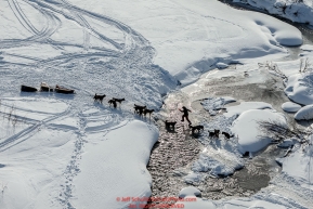 An Iditarod musher walks his dogs across a stretch of open water of the Happy River on the trail in the Alaska Range in Ptarmigan Valley on the way to Rohn from the Rainy Pass checkpoint during Iditarod 2016.  Alaska.  March 07, 2016.  Photo by Jeff Schultz (C) 2016 ALL RIGHTS RESERVED