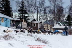 Scott Smith runs past village houses as he leaves the Nikolai checkpoint during Iditarod 2016.  Alaska.  March 08, 2016.  Photo by Jeff Schultz (C) 2016 ALL RIGHTS RESERVED