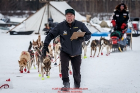 Volunteer checker Bruce Malard runs in front of Ed Stielstra towards a parking spot at the Nikolai checkpoint during Iditarod 2016.  Alaska.  March 08, 2016.  Photo by Jeff Schultz (C) 2016 ALL RIGHTS RESERVED