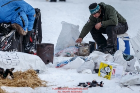 Norwegian musher Geir Idar Hjelvik heats his dinner in his hot dog water at the Nikolai checkpoint during Iditarod 2016.  Alaska.  March 08, 2016.  Photo by Jeff Schultz (C) 2016 ALL RIGHTS RESERVED