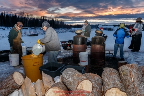 Local residents of Nikolai bring water to be heated for mushers at the Nikolai checkpoint during Iditarod 2016.  Alaska.  March 08, 2016.  Photo by Jeff Schultz (C) 2016 ALL RIGHTS RESERVED