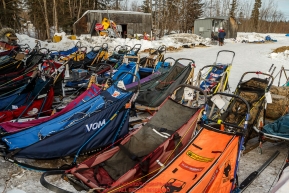 Musher's replacement sleds wait for their owners at the McGrath checkpoint during Iditarod 2016.  Alaska.  March 09, 2016.  Photo by Jeff Schultz (C) 2016  ALL RIGHTS RESERVED