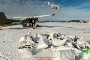 Volunteer Iditarod Air Force pilot O.E. Robbins and John Hooley take musher drop bags from the plane and stack them at the McGrath checkpoint during Iditarod 2016.  Alaska.  March 09, 2016.  Photo by Jeff Schultz (C) 2016  ALL RIGHTS RESERVED