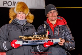 Mitch Seavey accepts the GCI Dorothy G. Page Halfway Award from GCI representative Tara Wheatland at the Huslia checkpoint during the 2017 Iditarod on Thursday night  March 9, 2017.Photo by Jeff Schultz/SchultzPhoto.com  (C) 2017  ALL RIGHTS RESERVED