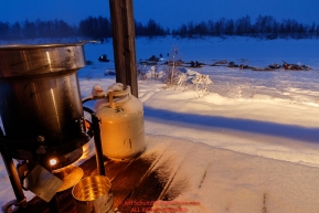Water is heated for mushers to thaw their meals during a snowfall at the Iditarod checkpoint in the morning on Friday, March 9th during the 2018 Iditarod Sled Dog Race -- AlaskaPhoto by Jeff Schultz/SchultzPhoto.com  (C) 2018  ALL RIGHTS RESERVED