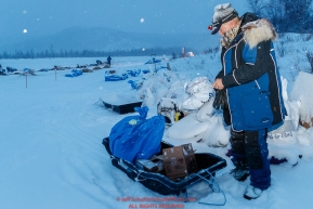 Volunteer checkpoint helper Rob Rose cleans up the yard during a snowfall at the Iditarod checkpoint on Friday, March 9th during the 2018 Iditarod Sled Dog Race -- AlaskaPhoto by Jeff Schultz/SchultzPhoto.com  (C) 2018  ALL RIGHTS RESERVED