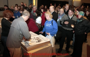 Thursday March 1, 2012  Attendees at the Iditarod musher banquet, held at the Dena'ina Civic and Convention Center in Anchorage, Alaska, line up for a special Iditarod ExxonMobil poster.