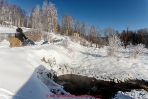 Scott Smith crosses over the Manley Hot Springs as steam rises from the warm water in the morning after leaving the checkpoint of Manley Hot Springs on March 10, 2015.   2015 Iditarod.(C) Jeff Schultz/SchultzPhoto.com - ALL RIGHTS RESERVED DUPLICATION  PROHIBITED  WITHOUT  PERMISSION