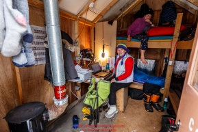 Volunteer comms Katy Kerris (on bunk) and Valerie Saiki inside the comms shack at the Ophir Checkpoint on Thursday March 10 during Iditarod 2016.  Alaska.    Photo by Jeff Schultz (C) 2016  ALL RIGHTS RESERVED