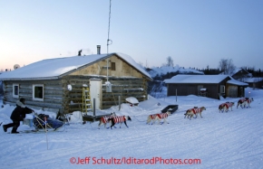 Sunday March 11, 2012   Hugh Neff runs past houses as dawn breaks at 25 degrees below zero while leaving Kaltag. Iditarod 2012.