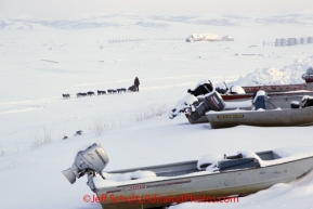 Sunday March 11, 2012  Sonny Lindner drives past boats as he leaves on the slough at Unalakleet.   Iditarod 2012.