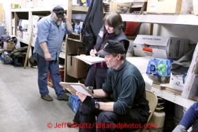 Logistics coordinator Teri Paton (middle) discuess veterinarian moves with chief vet Stu Nelson as race marshal Mark Nordman talks on the phone at the Unalakleet checkpoint on Monday March 11, 2013.Iditarod Sled Dog Race 2013Photo by Jeff Schultz copyright 2013 DO NOT REPRODUCE WITHOUT PERMISSION