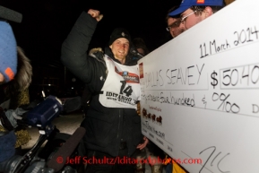 Dallas Seavey recieves his $50,000 winner's check from Wells Fargo Bank under the burl arch in Nome on Tuesday, March 11.  Iditarod Sled Dog Race 2014.PHOTO (c) BY JEFF SCHULTZ/IditarodPhotos.com -- REPRODUCTION PROHIBITED WITHOUT PERMISSION