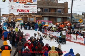 Sonny Lindner runs up the finish chute and under the burl arch in 5th place in Nome on Tuesday March 11th during the 2014 Iditarod Sled Dog Race.PHOTO (c) BY JEFF SCHULTZ/IditarodPhotos.com -- REPRODUCTION PROHIBITED WITHOUT PERMISSION