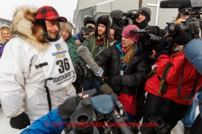 Martin Buser is interviewed and photographed by a slug of reporters at the finish line in Nome on Tuesday March 11th during the 2014 Iditarod Sled Dog Race.PHOTO (c) BY JEFF SCHULTZ/IditarodPhotos.com -- REPRODUCTION PROHIBITED WITHOUT PERMISSION