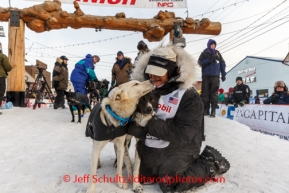 Jessie Royer gives her lead dog a hug under the burled arch finish line in Nome on Tuesday March 11th during the 2014 Iditarod Sled Dog Race.PHOTO (c) BY JEFF SCHULTZ/IditarodPhotos.com -- REPRODUCTION PROHIBITED WITHOUT PERMISSION