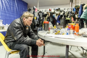 Lachlan Clarke has the 1,000 - mile stare as he rests in the community center as musher gear dries in the backgroud at the Tanana checkpoint on Wednesday morning  March 11th during the 2015 Iditarod.(C) Jeff Schultz/SchultzPhoto.com - ALL RIGHTS RESERVED DUPLICATION  PROHIBITED  WITHOUT  PERMISSION