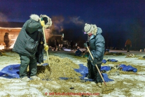 Volunteer helpers Tom Hyslop and Brita Heikkinen rake straw in the early morning hours on the banks of the Yukon river at the Tanana checkpoint on Wednesday morning  March 11th during the 2015 Iditarod.(C) Jeff Schultz/SchultzPhoto.com - ALL RIGHTS RESERVED DUPLICATION  PROHIBITED  WITHOUT  PERMISSION