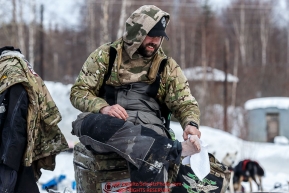 Rick Casillo dries his feet at the Ruby Checkpoint after traveling through overflow on the trail from Cripple during the 2016 Iditarod.  March 11, 2016    Photo by Jeff Schultz (C) 2016  ALL RIGHTS RESERVED