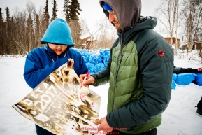 Nicolas Petit signs an ExxonMobil Iditarod poster for a student at the Koyukuk checkpoint during the 2017 Iditarod on Saturday afternoon March 11, 2017.Photo by Jeff Schultz/SchultzPhoto.com  (C) 2017  ALL RIGHTS RESERVED