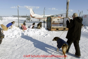 Sunday March 11, 2012   Volunteer Comms Grant Jacobson walks a dropped dog to a staging area ready to get on the Penair Caravan for the trip back to Anchorage from Unalakleet. Iditarod 2012.