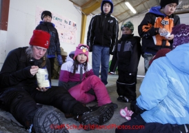 Monday March 12, 2012  Aliy Zirkle eats amidst young Elim school kids in the fire hall at Elim. Iditarod 2012.